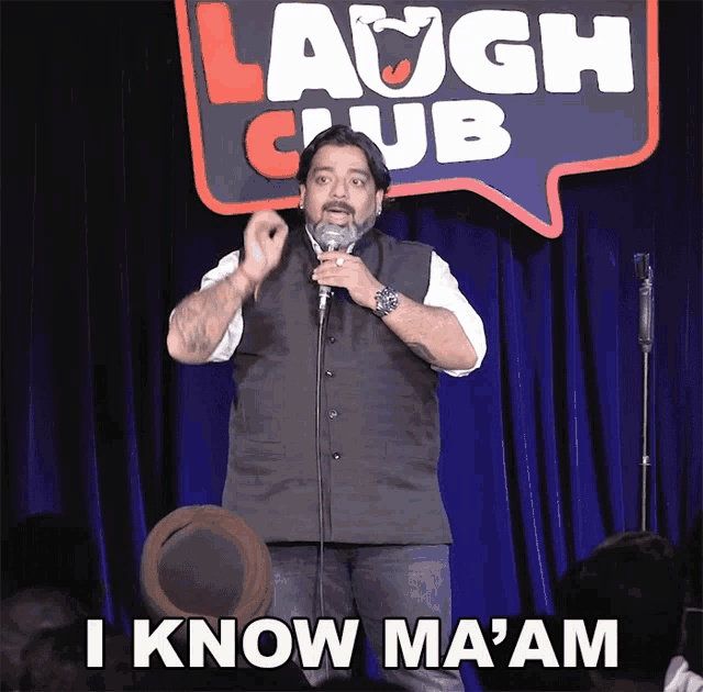 a man is giving a speech in front of a laugh club sign