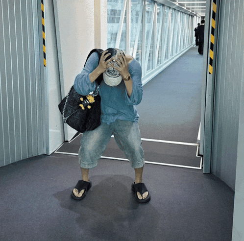 a person covering their face with their hands while holding a purse