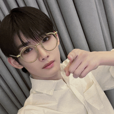 a young man wearing glasses and a white shirt is taking a selfie