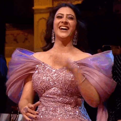 a woman in a pink dress is laughing while standing in a room .
