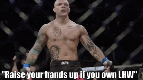 a man in a ufc uniform is standing in a ring with his hands up