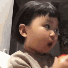 a little girl is making a funny face while holding an apple .
