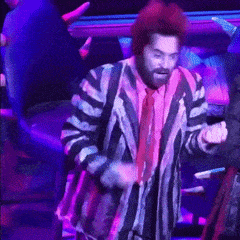 a man in a striped jacket and tie is dancing on a stage .