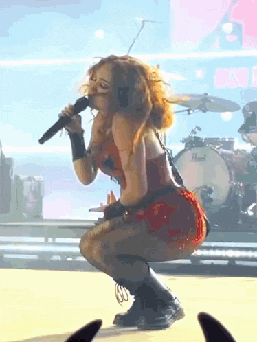 a woman is singing into a microphone on a stage with a pearl drum in the background