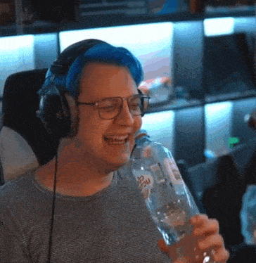 a man with blue hair and glasses is wearing headphones and holding a bottle of water .