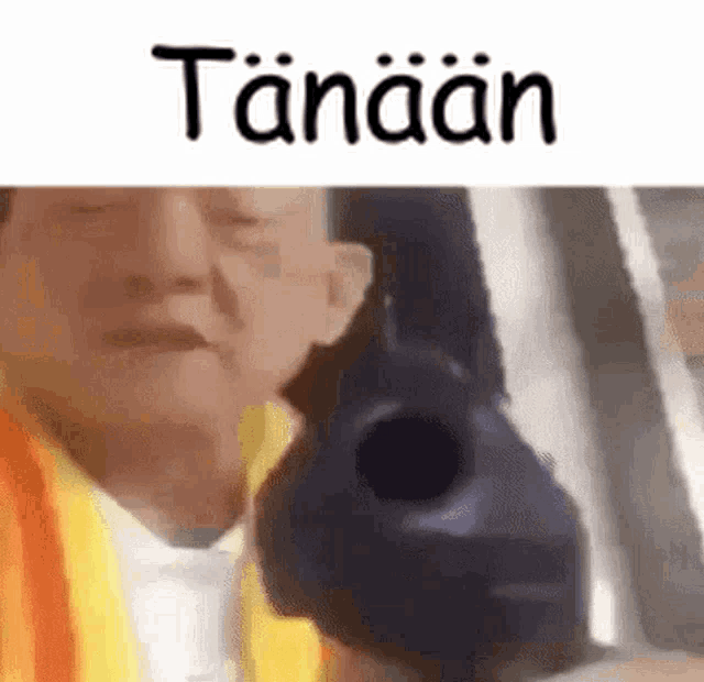 a man is holding a gun in front of his face and the word tanaan is written above him .