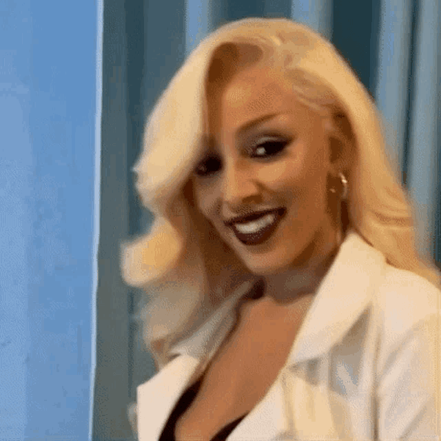 a woman with blonde hair and red lipstick is wearing a white jacket .