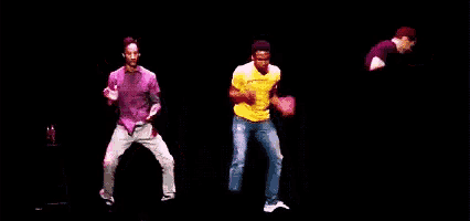 a man in a yellow shirt is dancing with another man in a pink shirt in the background .