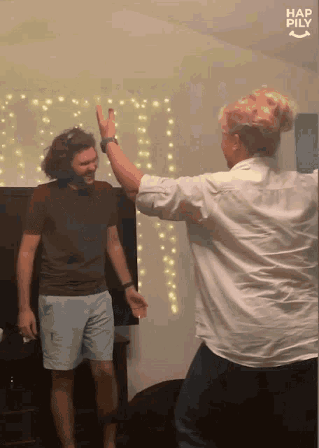 a man and a woman are giving each other a high five in front of a wall that says hap pily on it