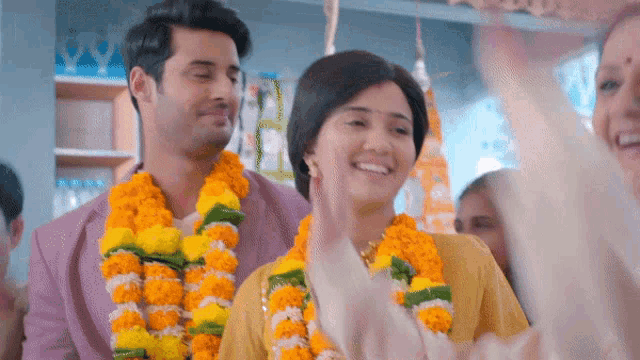 a man and a woman are wearing garlands of flowers