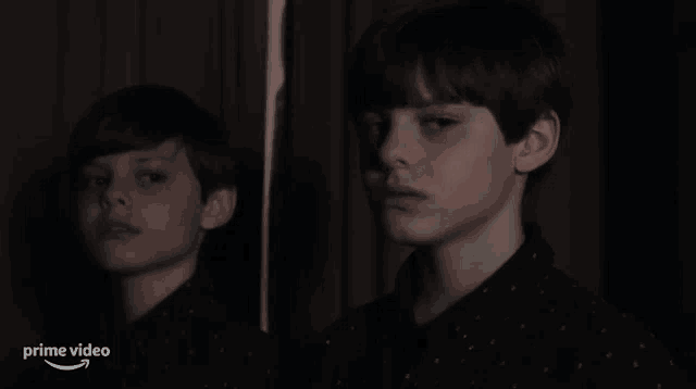 a young boy is looking at his reflection in a mirror with the words prime video below him