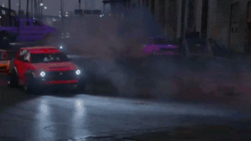 a red car is driving down a street with other cars .