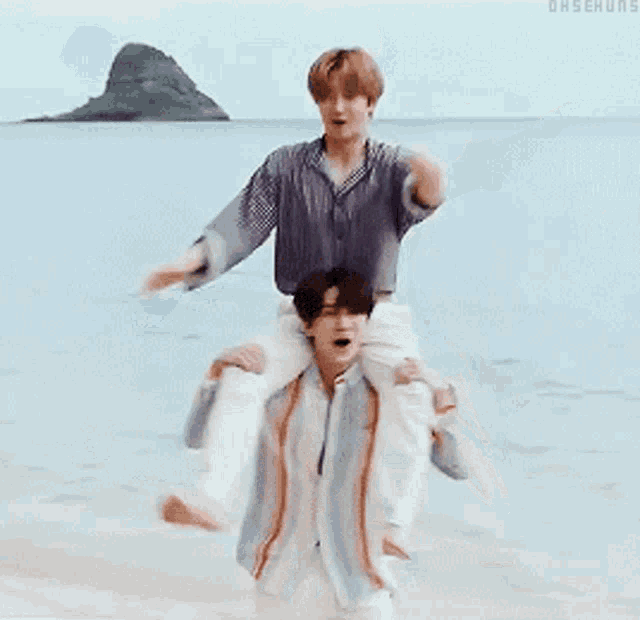 a man is carrying another man on his shoulders in the water