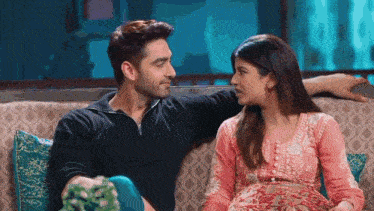 a man and a woman are sitting on a couch and looking at each other