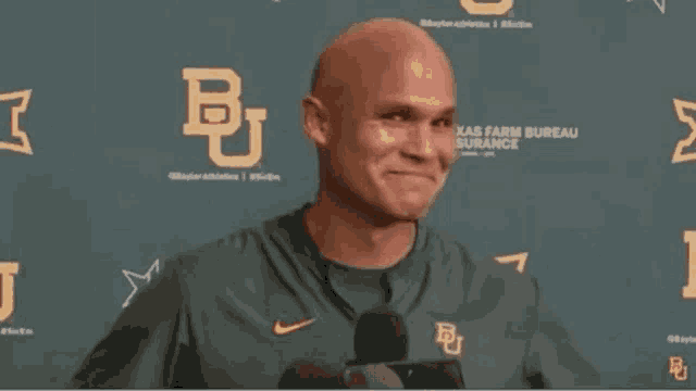 a bald man wearing a green nike shirt with the letter b on it