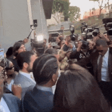 a crowd of people are gathered in front of a building taking pictures