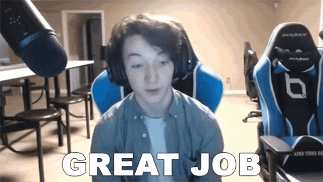 a man wearing headphones is sitting in front of a microphone saying great job