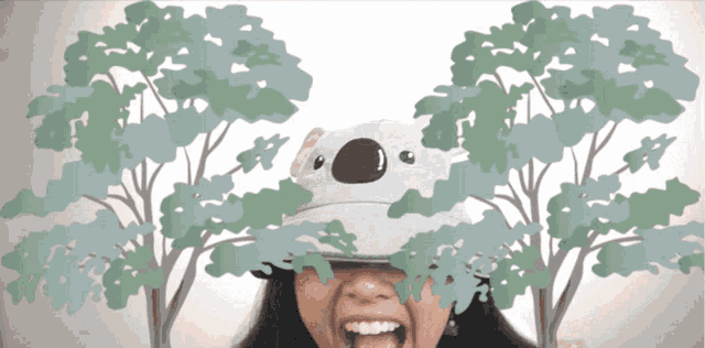 a woman wearing a hat with a koala on it surrounded by trees