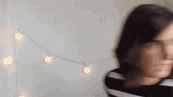 a blurry picture of a woman 's face with a string of lights in the background