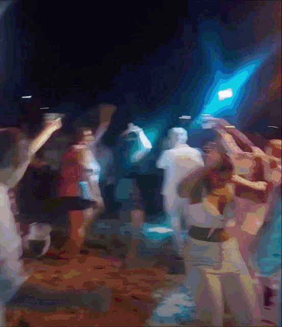 a blurry picture of a crowd of people dancing in a dark room