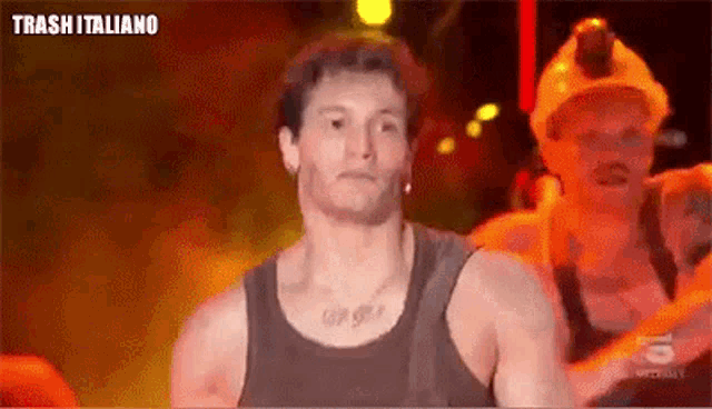 a man in a tank top is standing on a stage wearing a helmet .