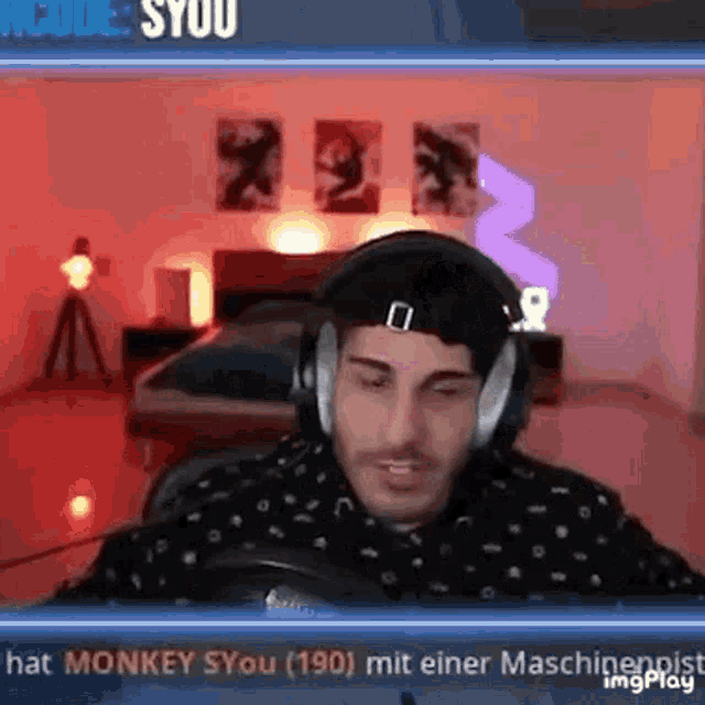 a man wearing headphones and a hat is sitting in front of a microphone in a room .