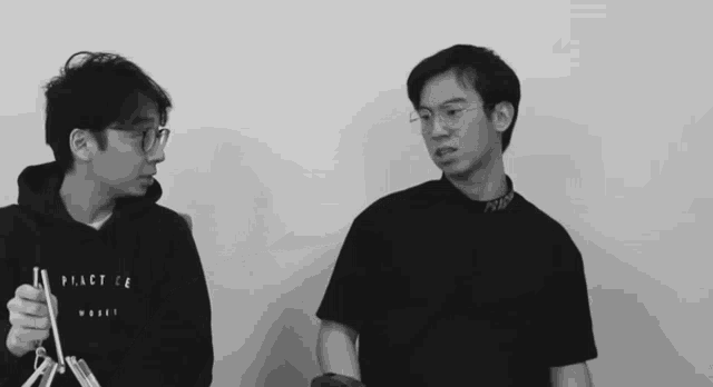 a black and white photo of two young men one wearing a black shirt that says peace on it