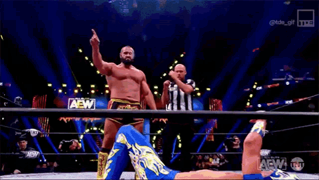 a wrestler is giving the middle finger while standing in a ring with a referee .