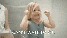 a little girl is standing in front of a mirror and making a funny face .