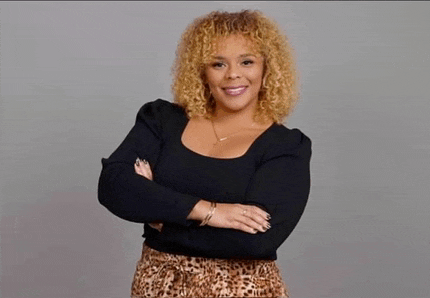 a woman with curly hair is standing with her arms crossed and smiling for the camera .