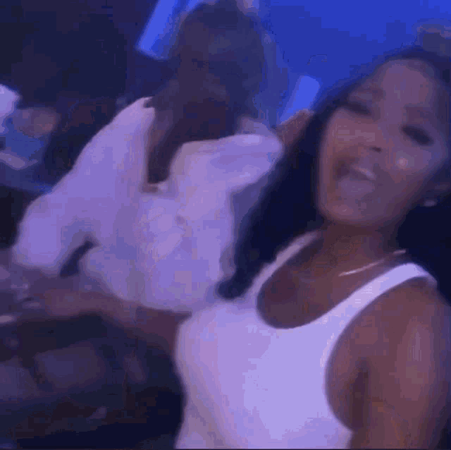 a woman in a white tank top is dancing with a man in a white shirt .