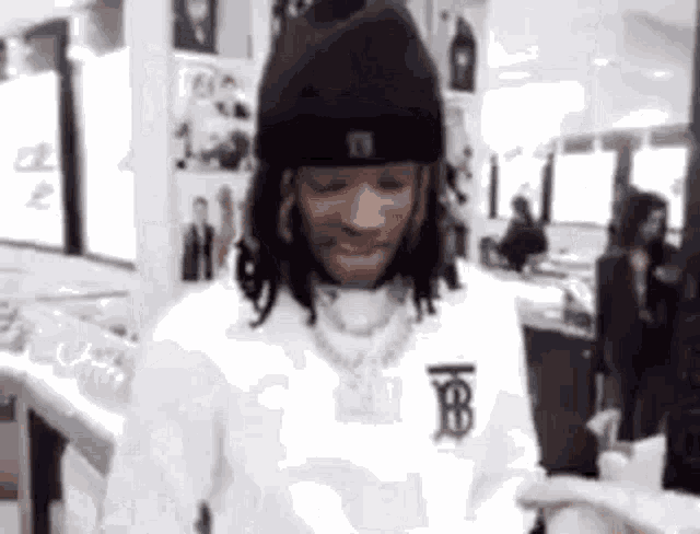 a man wearing a black hat and a white shirt is looking at a cell phone .