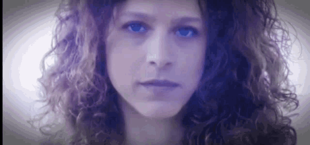 a close up of a woman 's face with curly hair .
