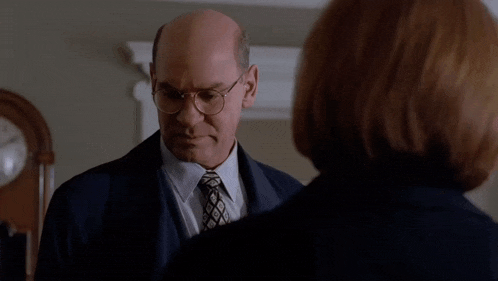 a man in a suit and tie is talking to a woman with the words " what the hell 's the point in all of this "