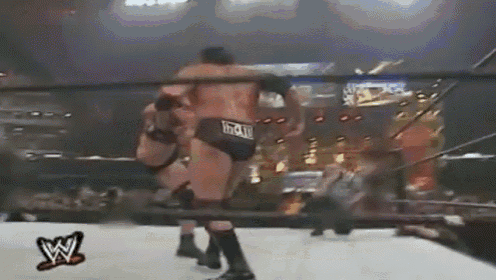 two men are wrestling in a ring with a w logo on the side of the ring