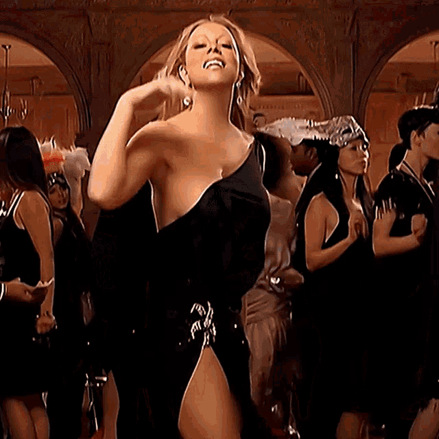 a woman in a black dress is dancing in a crowded room