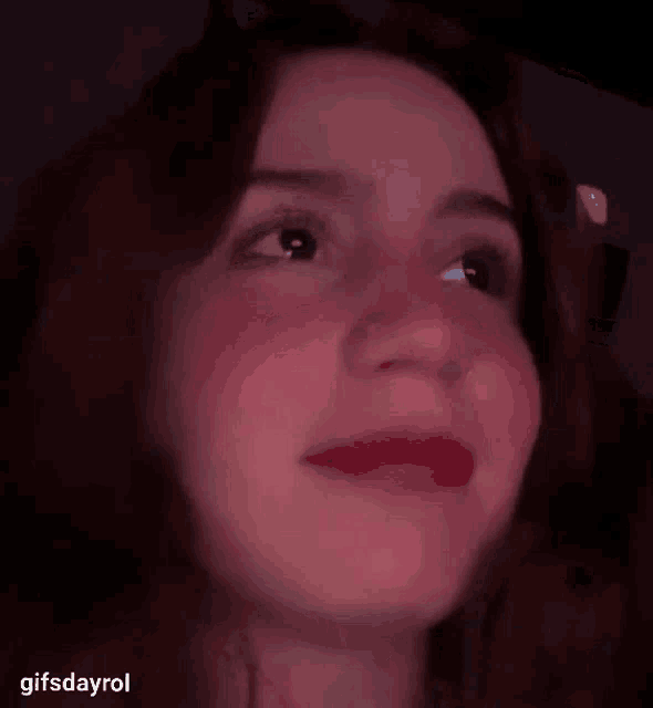 a close up of a woman 's face with red lipstick and a dark background .