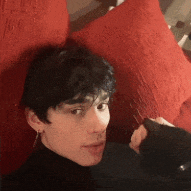 a young man laying on a bed with a red pillow