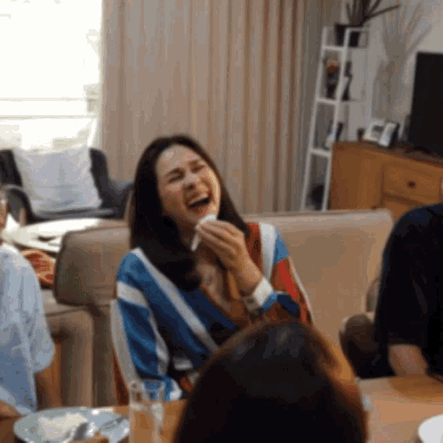 a woman is laughing while sitting at a table