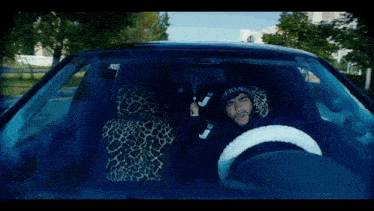 a man is driving a car with a leopard print seat cushion