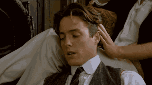 a man in a suit and tie is laying on a couch with his eyes closed