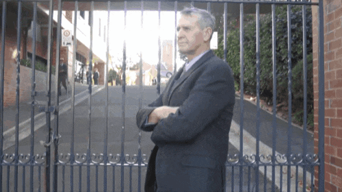 a man in a suit is standing in front of a fence with a sign that says 30