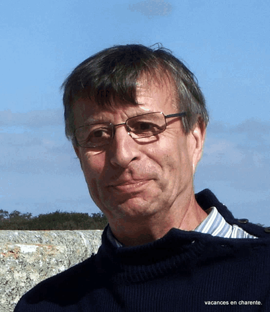 a man wearing glasses and a blue sweater has the word vacances on the bottom