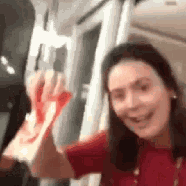 a woman in a red shirt is smiling and holding a piece of bloody paper .