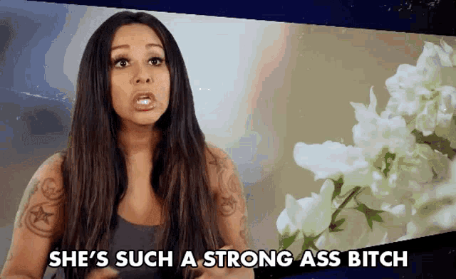 a woman says she 's such a strong ass bitch in front of some white flowers