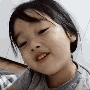a little girl is making a funny face and smiling at the camera .