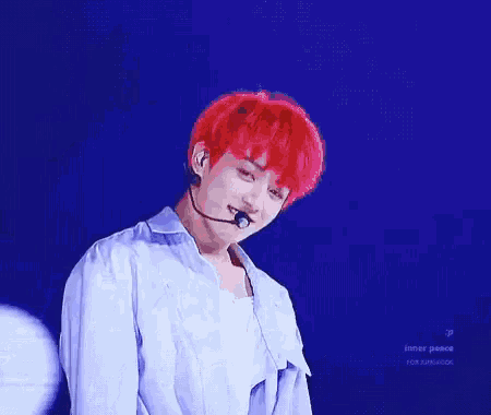 a young man with red hair is holding a microphone in his mouth while standing on a stage .