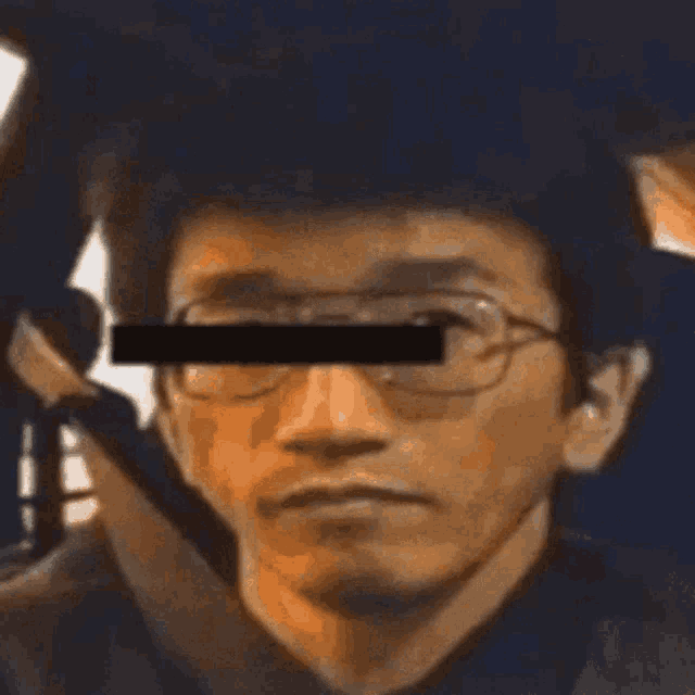 a man wearing glasses and a blindfold is sitting in a car and looking at the camera .