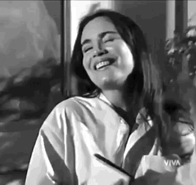a woman is smiling in a black and white photo while holding a pen .