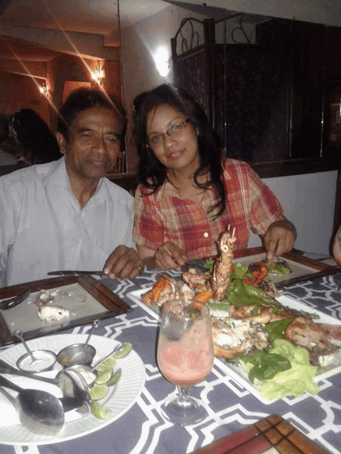 a man and a woman sit at a table with plates of food on it